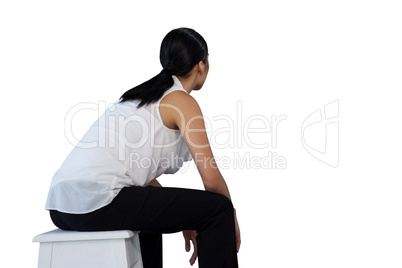 Side view of woman sitting on stool
