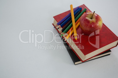 Apple and color pencils on book on white background