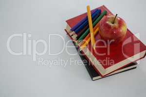 Apple and color pencils on book on white background