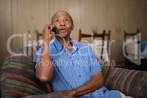 Senior man talking on mobile phone while sitting on sofa