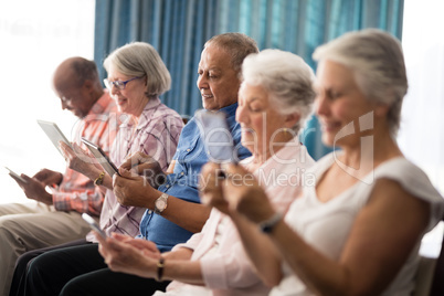 Smiling senior people using digital tablets while sitting on chairs