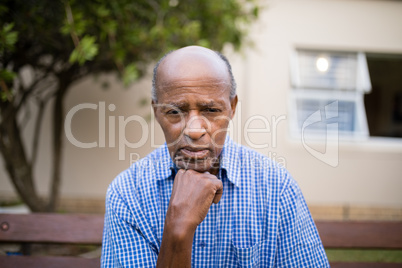 Depressed senior man sitting with hand on chin