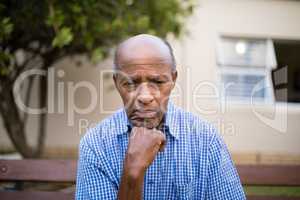 Depressed senior man sitting with hand on chin