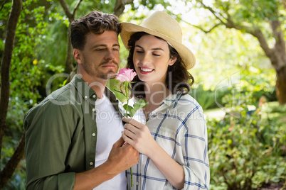 Smiling couple looking at flower in garden