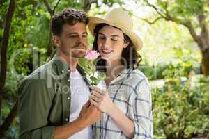 Smiling couple looking at flower in garden