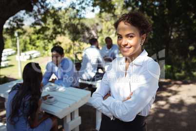 Waitress standing with arms crossed at outdoor restaurant