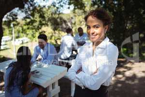 Waitress standing with arms crossed at outdoor restaurant