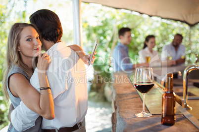 Couple embracing while using mobile phone