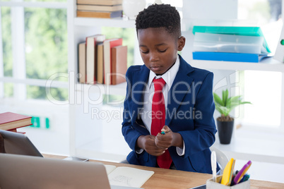 Businessman holding pen while sitting at desk
