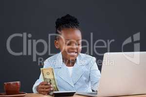 Smiling businesswoman calculating finance while using laptop