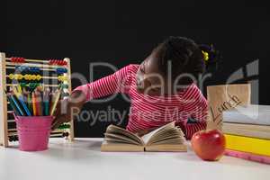 Schoolgirl using abacus against black background