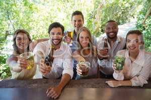 Portrait of smiling friends showing alcohol at counter