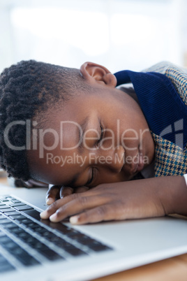 Close-up of businessman taking a nap on laptop at desk