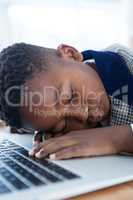 Close-up of businessman taking a nap on laptop at desk