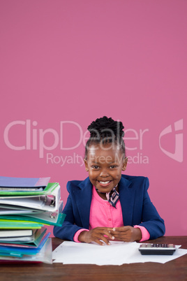 Portrait of smiling businesswoman doing paperwork at desk