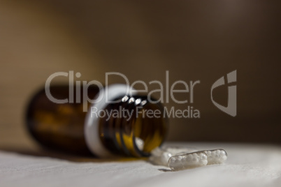 Pills coming out of a little glass bottle.