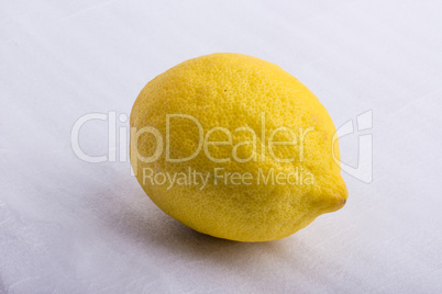 A yellow lemon on a white surface A yellow lemon on a white surface