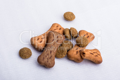 Bits of dog food and treats on a white surface.