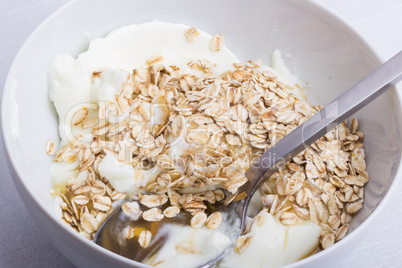 A white plate half full with oats with yogurt and honey, with a