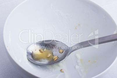 A white plate and a spoon, with the remains of a breakfast.