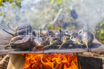 Eggplants cooking on a metal plate over open fire