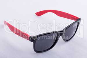 Sun glasses with red temples on a white surface