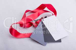 Three cards, white, grey and black, on a red strap.