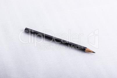 A black pencil, on a white surface.