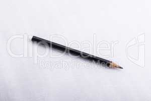 A black pencil, on a white surface.
