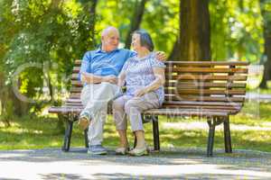 Senior couple relaxed talking on the park bench