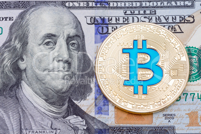 Golden blue bitcoin on one hundred bankmote background.