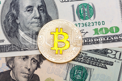 Close up of golden yellow bitcoin on US dollars background.