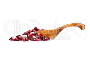 Mottled haricot legumes beans in the wooden spoon, isolated on w