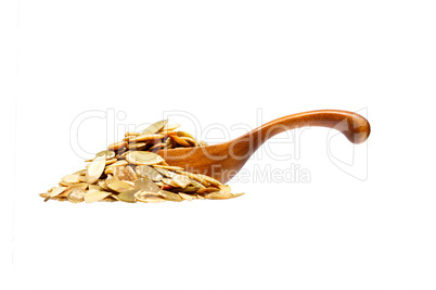 Pumpkin seeds in the wooden spoon, isolated on white background.