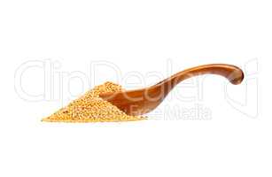 Yellow mustard seeds in the wooden spoon, isolated on white back