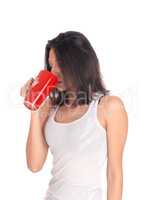Hispanic woman drinking from a red mug.