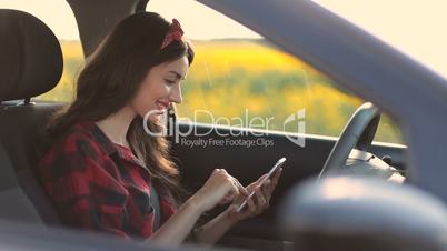 Charming woman using smartphone while driving car