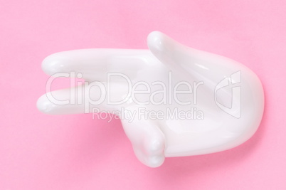 Ceramic stand with hand shape on pink background