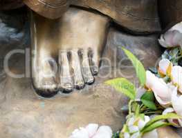 Foot of bronze statue with flowers
