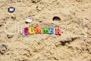 Inscription summer on sand with seashells