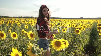 Beautiful lady walking in summer sunflower field