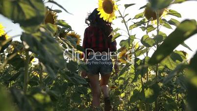 Sexy young woman running through sunflower field