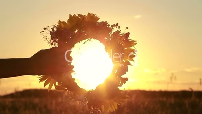 Female hands holding flower wreath in sunset light