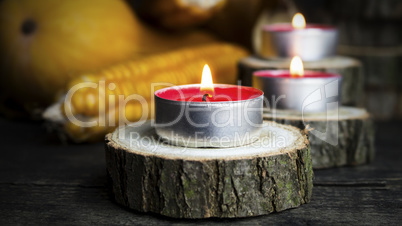 Burning Candles With Pumpkins, Corncob, autumn leaves in the bac