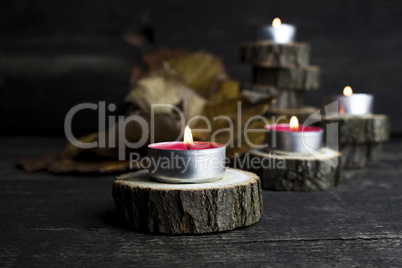 Christmas candles burning, decoration on wooden logs resting on