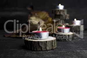 Christmas candles burning, decoration on wooden logs resting on