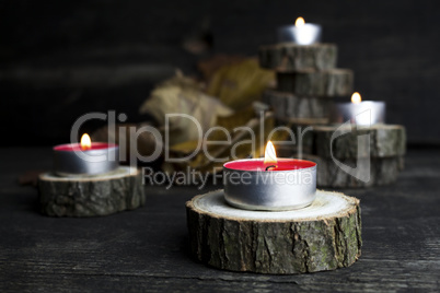 Christmas candles burning, decoration with wooden logs resting o