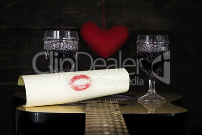 Kiss On White Paper Resting on Acoustic Guitar With Vine Glasses