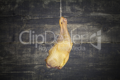 Smoked Chicken Leg Hanging on the Rope Against Wooden Background