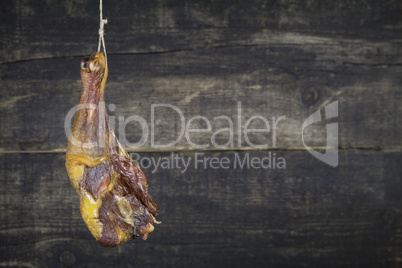 Smoked Chicken Leg Hanging on the Rope Against Wooden Background